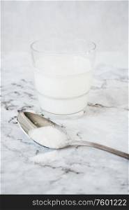 Glass of milk and spoon of sugar