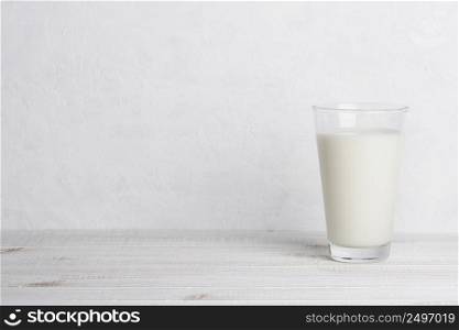Glass of milk on white wooden table and white background with side copy space