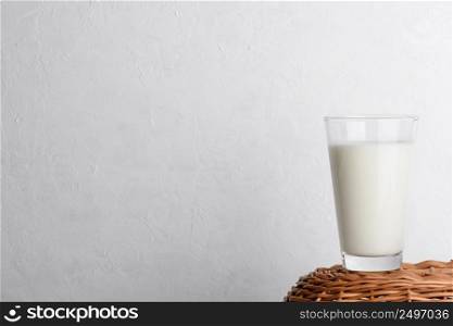 Glass of milk on wicker basket and white wall background as copy space