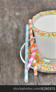 Glass of milk with striped straws on old wooden background