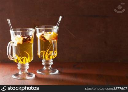 glass of mulled apple cider with orange and spices, winter drink background