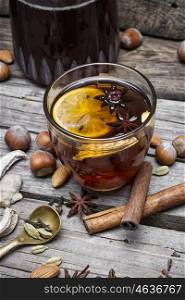 glass of mulled wine with almonds,cinnamon and anise on background of carafe of wine