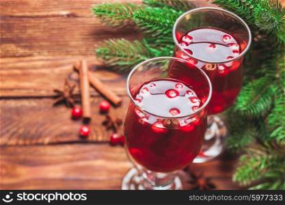 Glass of mulled wine with cranberry and scented cinnamon sticks on a wooden table. Mulled wine with cranberries. Winter drink