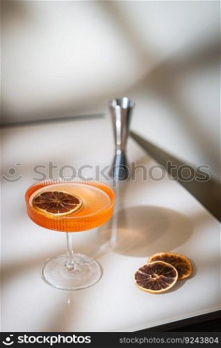 Glass of orange cocktail decorated with orange on light background with bright beautiful shadows. Glass of orange cocktail