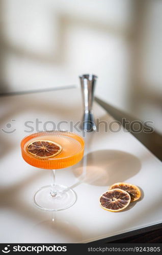 Glass of orange cocktail decorated with orange on light background with bright beautiful shadows. Glass of orange cocktail