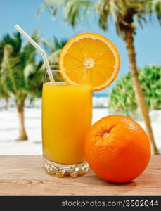 Glass of orange juice on a beach table