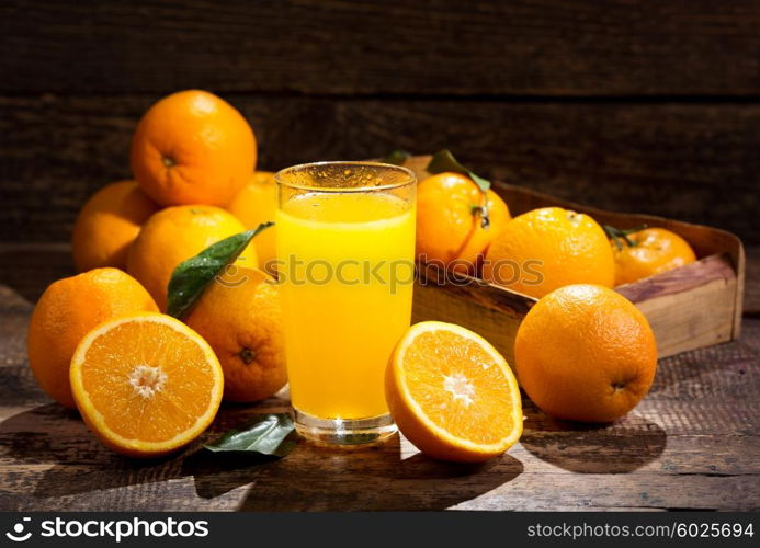 glass of orange juice with fresh fruits on wooden background