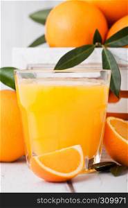 Glass of organic fresh orange smoothie juice with raw oranges in white wooden box