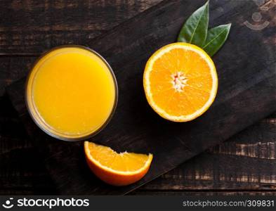 Glass of organic fresh orange smoothie juice with raw oranges on dark wooden background.Top view