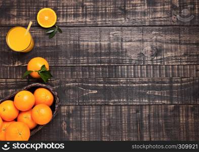Glass of organic fresh orange smoothie juice with raw oranges on dark wooden background.Top view.