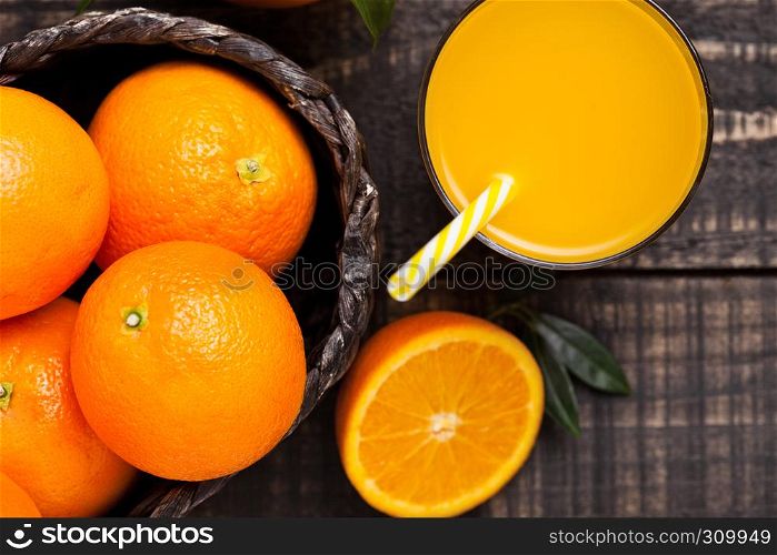 Glass of organic fresh orange smoothie juice with raw oranges on dark wooden background.Top view.