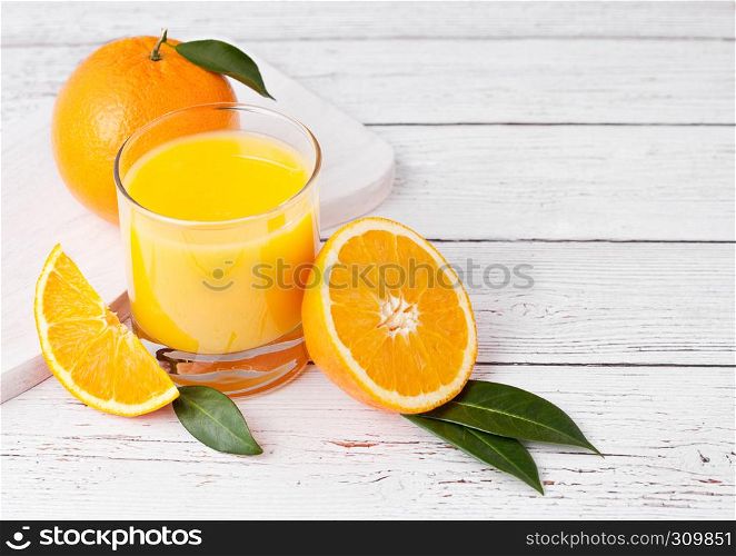 Glass of organic fresh orange smoothie juice with raw oranges on white wooden background