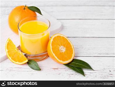 Glass of organic fresh orange smoothie juice with raw oranges on white wooden background