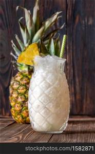 Glass of Pina colada cocktail garnished with pineapple wedge