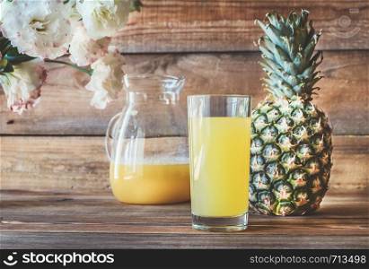 Glass of pineapple juice with fresh pineapple on the wooden background