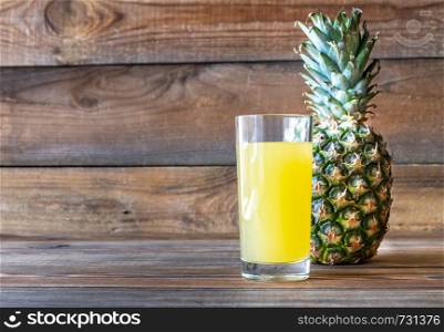 Glass of pineapple juice with fresh pineapple on the wooden background