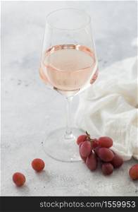 Glass of pink rose wine with grapes and empty glass on light background with white linen cloth.