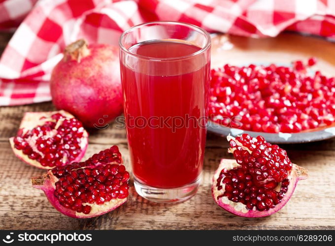 glass of pomegranate juice with fresh fruits on wooden table