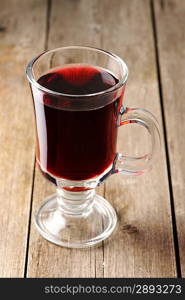 Glass of red mulled wine on wooden table