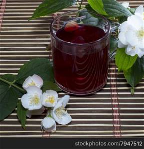 glass of red tea on a rug with a flower