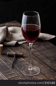Glass of red wine and vintage corkscrew in the kitchen on wooden table
