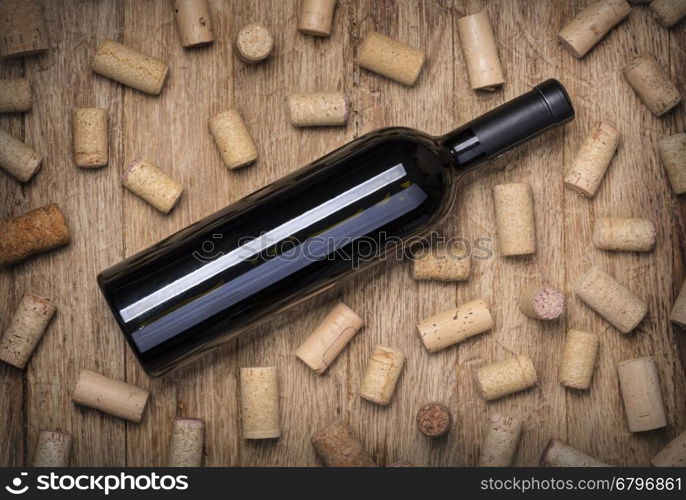 Glass of red wine, bottle and corks on rustic wooden table. Top view with copy space