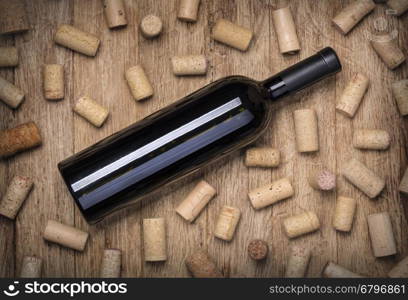 Glass of red wine, bottle and corks on rustic wooden table. Top view with copy space