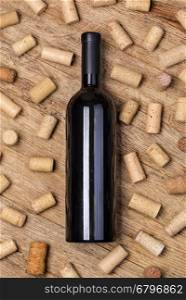 Glass of red wine, bottle and corks on rustic wooden table. Top view with copy space
