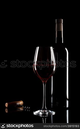 Glass of red wine, bottle and corkscrew on a black glass