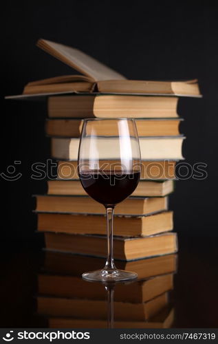 Glass of red wine on a reflective surface with books