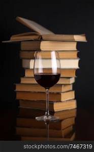 Glass of red wine on a reflective surface with books