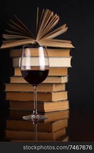 Glass of red wine on a reflective surface with books