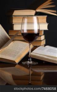 Glass of red wine on a reflective surface with books