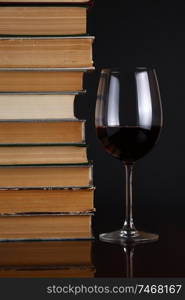 Glass of red wine on a reflective surface with books