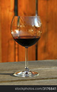 Glass of red wine on old rustic table, vertical