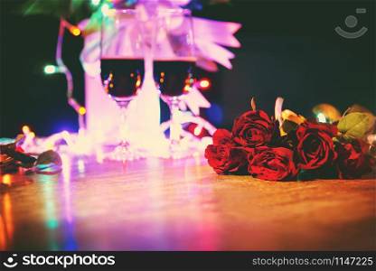 Glass of red wine on table Valentines dinner romantic love concept / Romantic table setting decorated with champagne glass wine roses flower on rustic table dinner night light