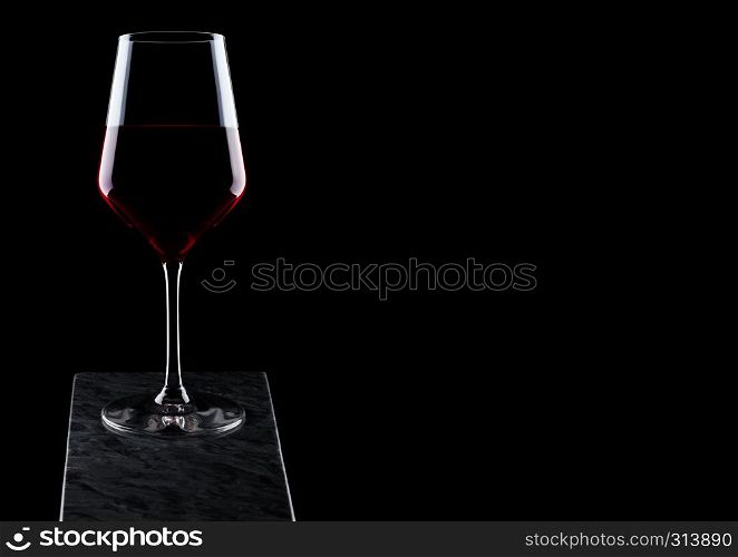 Glass of red wine on wooden board on black background.