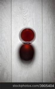 Glass of red wine on wooden table. Top view