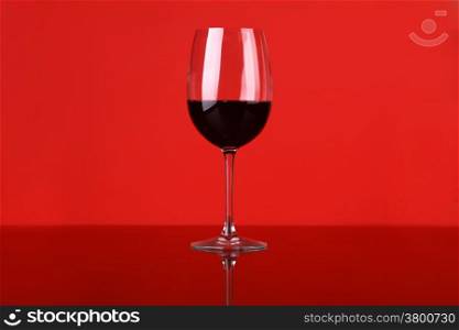 Glass of red wine over a red background