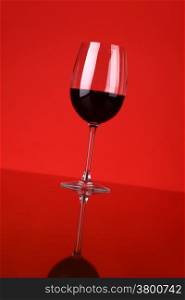 Glass of red wine over a red background