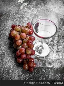 glass of red wine with a branch of fresh grapes. On a rustic background.. glass of red wine with a branch of fresh grapes.