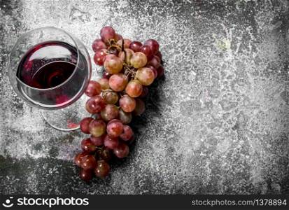 glass of red wine with a branch of fresh grapes. On a rustic background.. glass of red wine with a branch of fresh grapes.