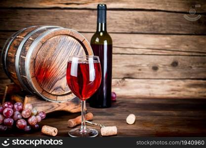 Glass of red wine with a brush of grapes on the table. On a wooden background. . Glass of red wine with a brush of grapes on the table.