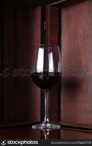 Glass of red wine with a wooden case in the background