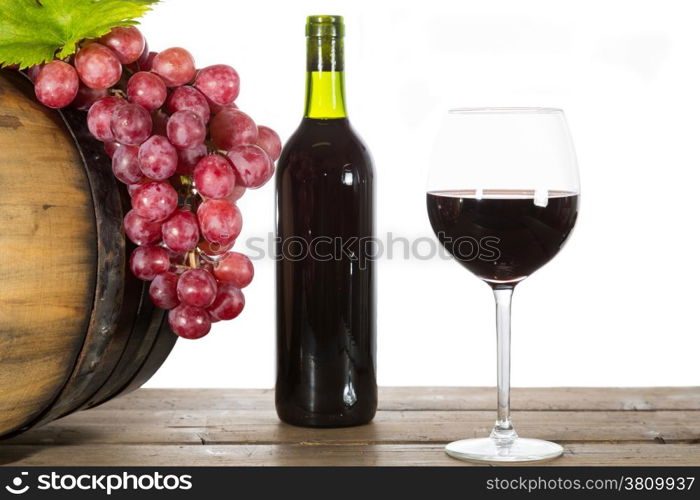 Glass of red wine with some grapes and oak barrels