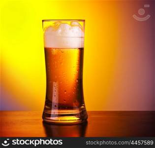 Glass of refreshing beer on wooden table, closeup on cold alcoholic drink over yellow background, food still life, party lifestyle, celebrating Oktoberfest holiday, traditional German lager