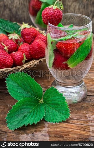 glass of refreshing strawberry cocktail. glass with drink of strawberries and mint on the background of the basket full berries.Selective focus.Photo tinted