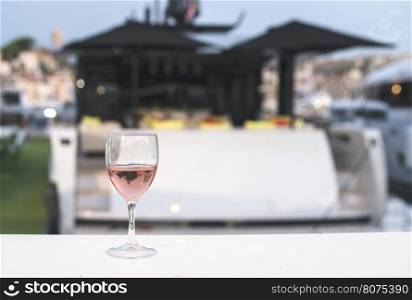 Glass of rose wine and a yacht on the background