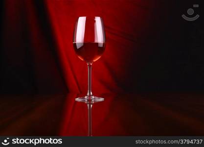 Glass of rose wine over a draped background lit red