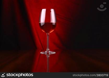 Glass of rose wine over a draped background lit red